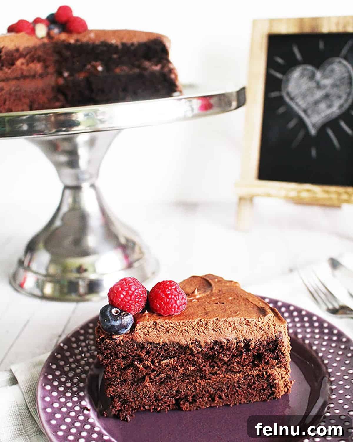 25 Festive Vegan Christmas Desserts 3 Slices of Vegan Chocolate Cake on a purple plate next to a cake pedestal