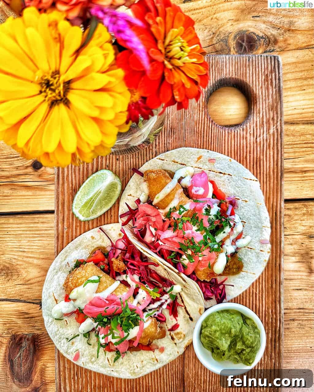 Downtown Victoria's Food Scene 2 Two vibrant fish tacos elegantly presented on a rustic wooden board, garnished with colorful edible flowers, at 10Acres Bistro in Victoria BC, Canada.
