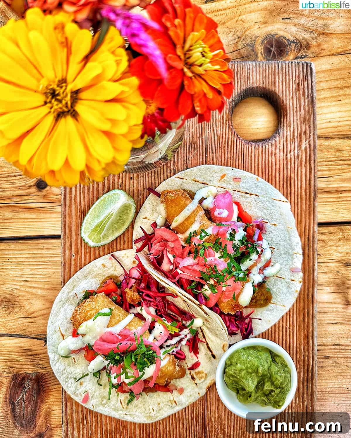 Downtown Victoria's Food Scene 6 Two enticing fish tacos on a wooden board, decorated with small, colorful flowers, against a blurred background, at 10 Acres Bistro in Victoria BC, Canada.