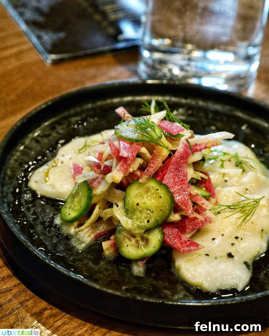 Banff Unleashed 8 Tuna crudo with vibrant vegetables on a dark plate, showcasing fresh ingredients.