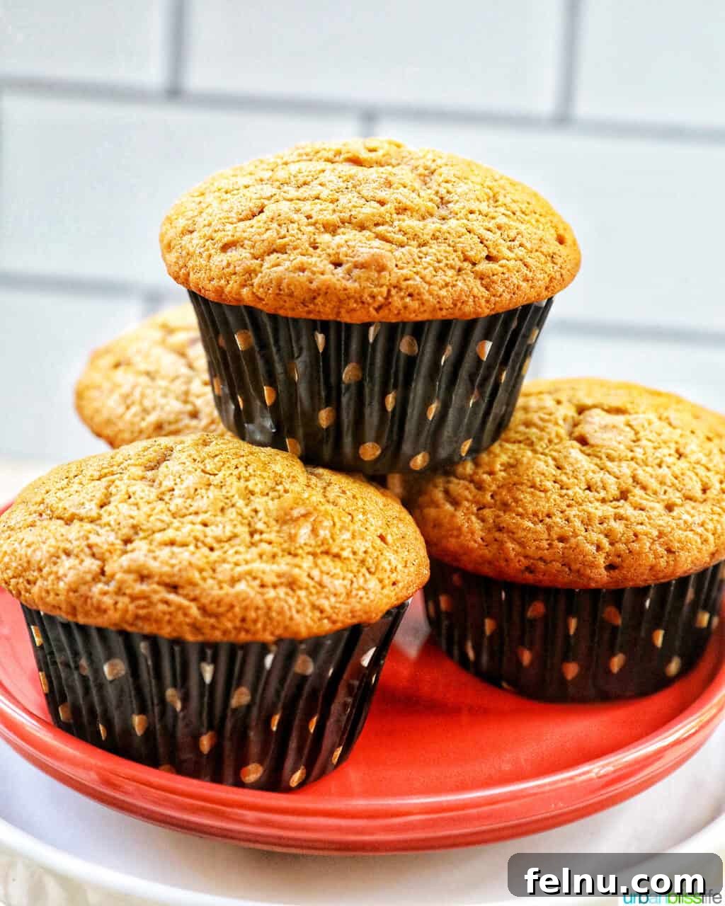 Pumpkin Banana Bliss Muffins 2 Pumpkin banana muffins stacked on an orange plate.