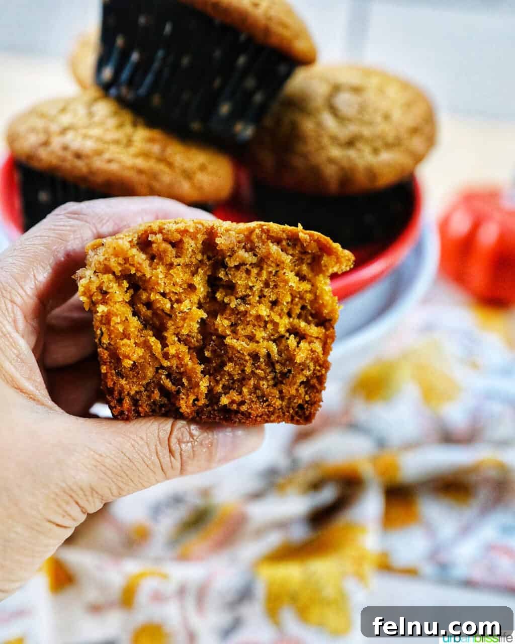 Pumpkin Banana Bliss Muffins 15 Hand holding a pumpkin banana muffin split in half revealing the inside.