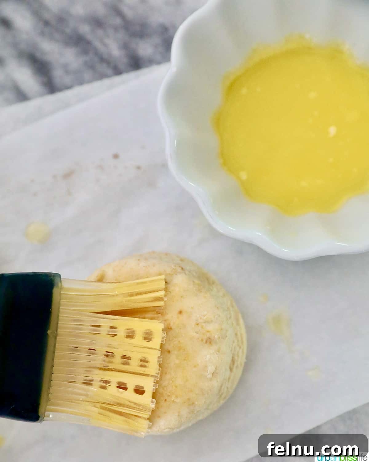 Fluffy Air Fryer Biscuits 14 pastry brush brushing melted butter onto an air fried biscuit.