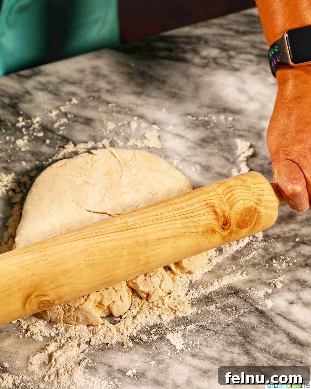 Fluffy Air Fryer Biscuits 9 hands and rolling pin rolling biscuit dough flat on a marble counter.
