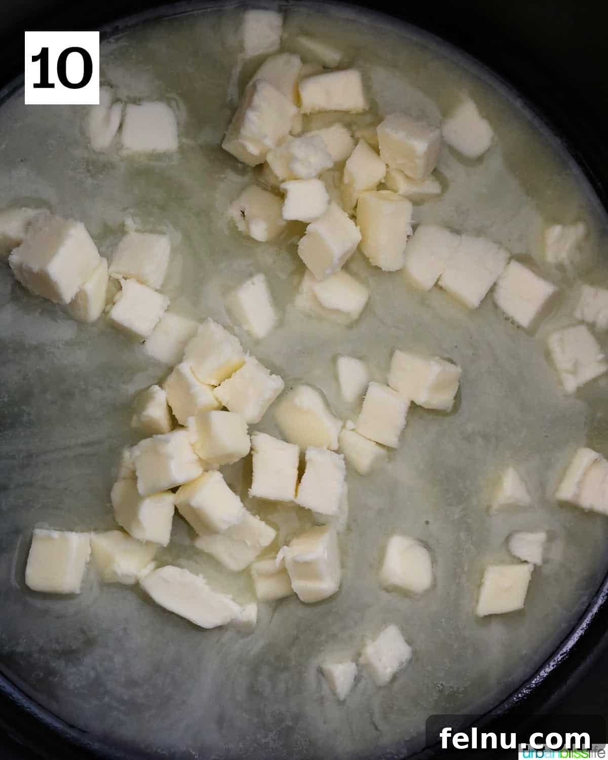 Small cubes of unsalted butter are melting in a warm pan, forming the base for the rich sage butter sauce.