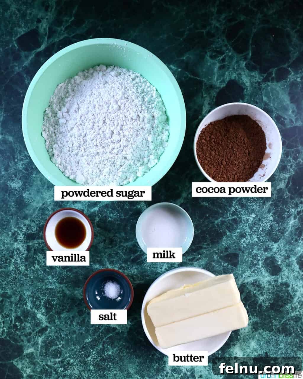 Effortless Decadent Chocolate Buttercream 4 Small bowls containing the essential ingredients for easy chocolate buttercream frosting, including powdered sugar, cocoa powder, and softened butter.