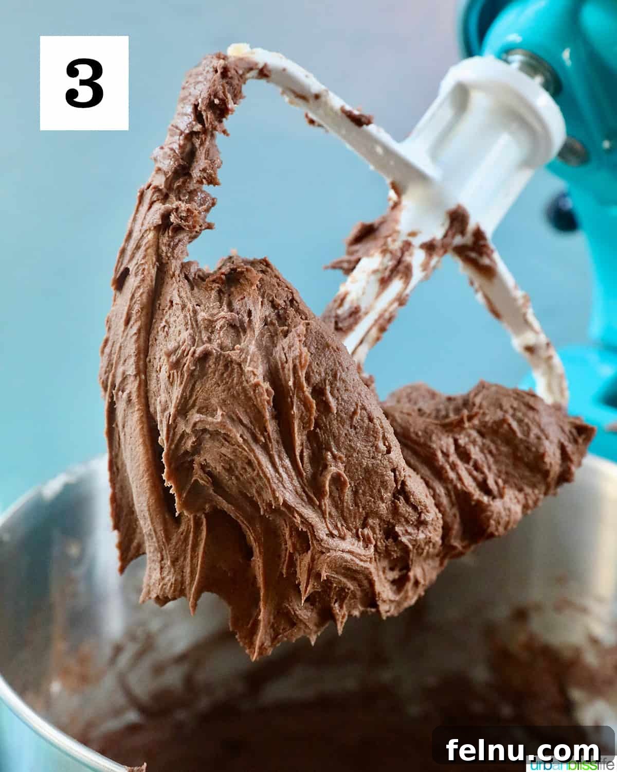 Effortless Decadent Chocolate Buttercream 7 A close-up of finished chocolate buttercream frosting on a stand mixer paddle, showcasing its smooth, consistent texture.