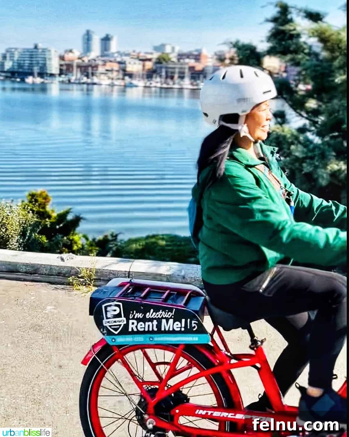 A woman smiling while riding an e-bike through a scenic park in Victoria, BC, Canada.