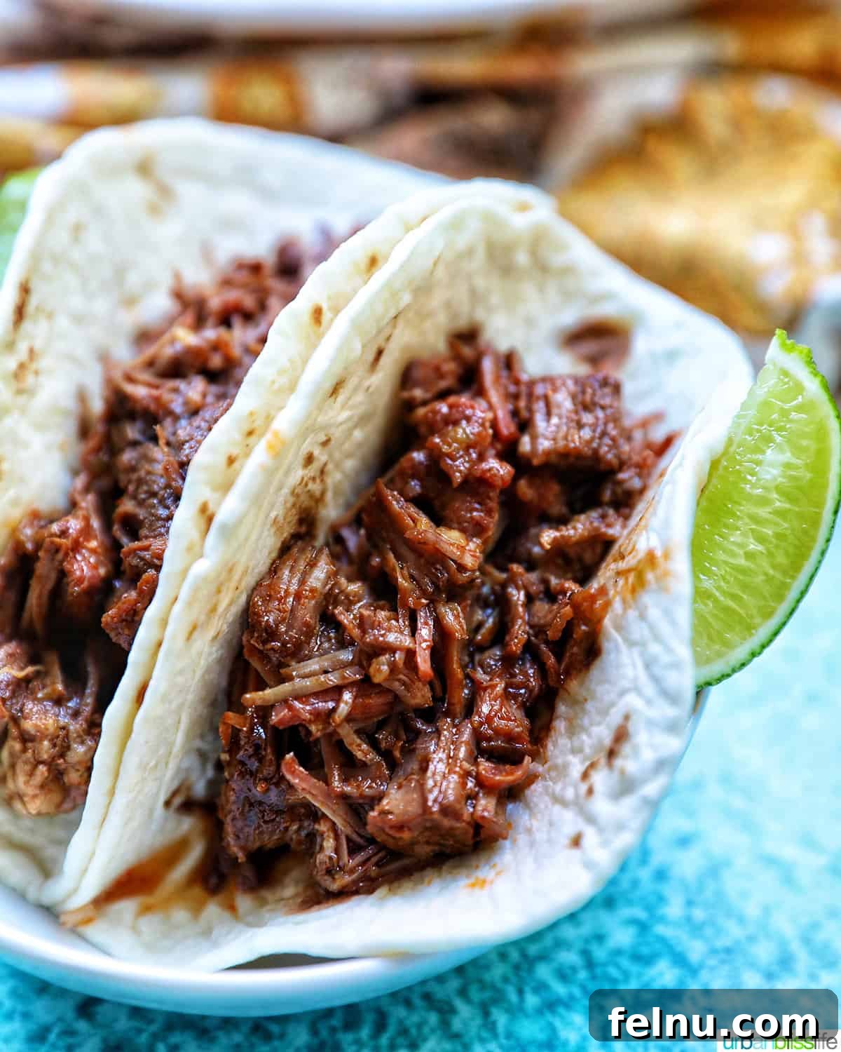 Slow-Cooker Fiesta Shredded Beef 16 Mexican shredded beef in taco shells with lime wedges.
