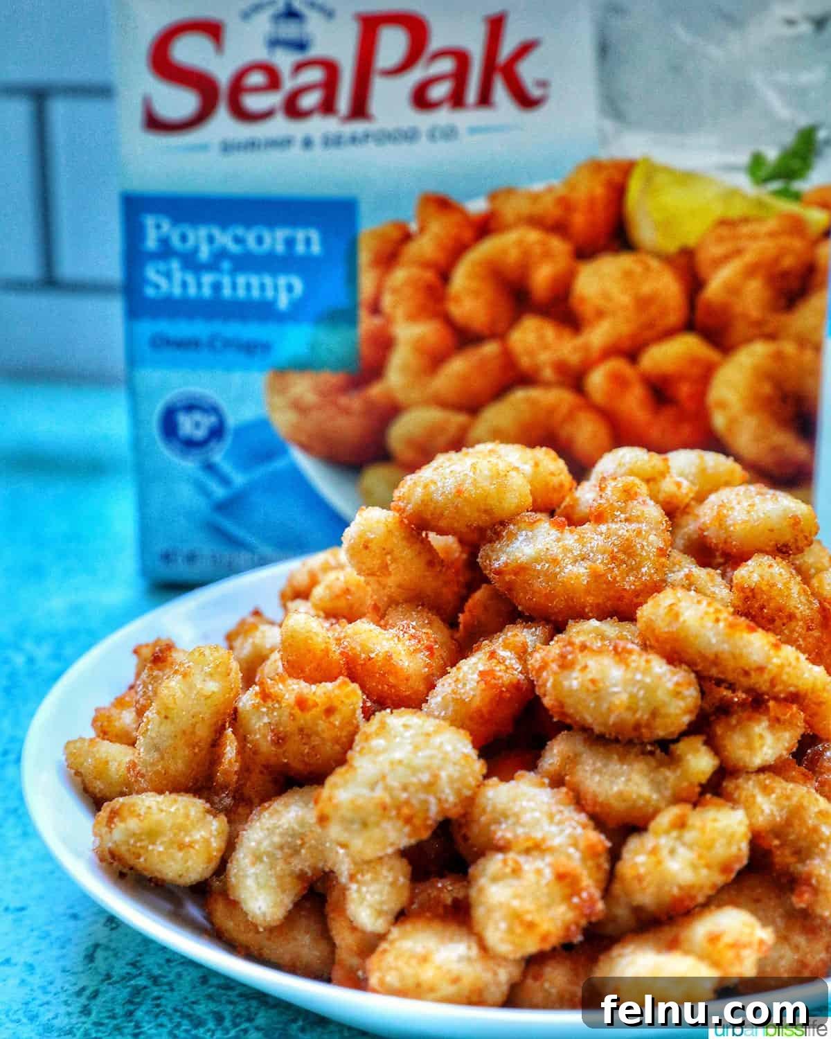 Crispy Air Fryer Popcorn Shrimp 4 A bowl overflowing with crispy air fryer popcorn shrimp, positioned next to its original frozen packaging, highlighting the ease of preparation.