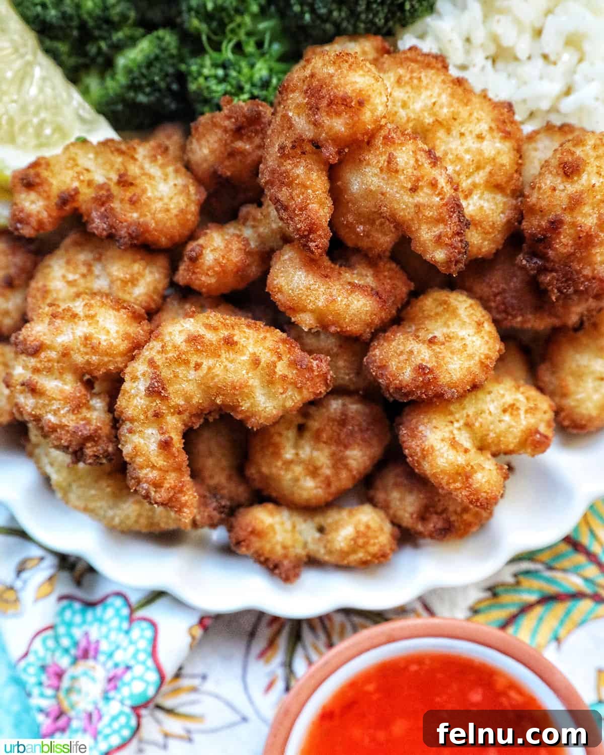 Crispy Air Fryer Popcorn Shrimp 8 A plate of golden-brown air fryer popcorn shrimp, perfectly cooked and ready to be dipped, with sauce on the side.