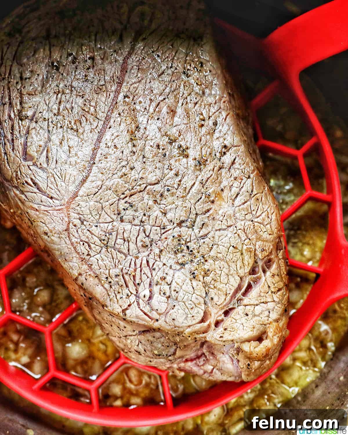Tender Instant Pot Sirloin Tip Roast 11 cooked sirloin tip roast in the Instant pot on a red sling with carrots and potatoes around it.
