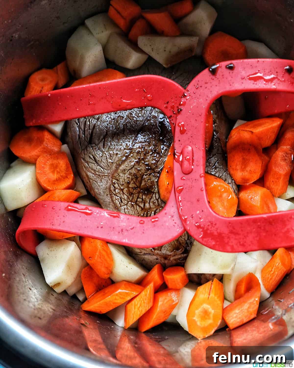 Tender Instant Pot Sirloin Tip Roast 12 sirloin tip roast, carrots, and potatoes in a red sling in the Instant Pot.