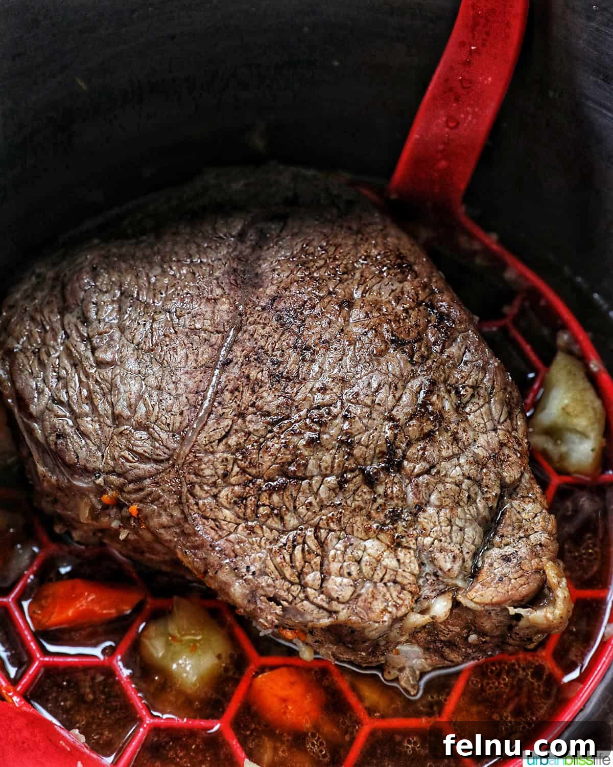 Tender Instant Pot Sirloin Tip Roast 14 cooked sirloin tip roast in the Instant pot on a red sling with carrots and potatoes around it.