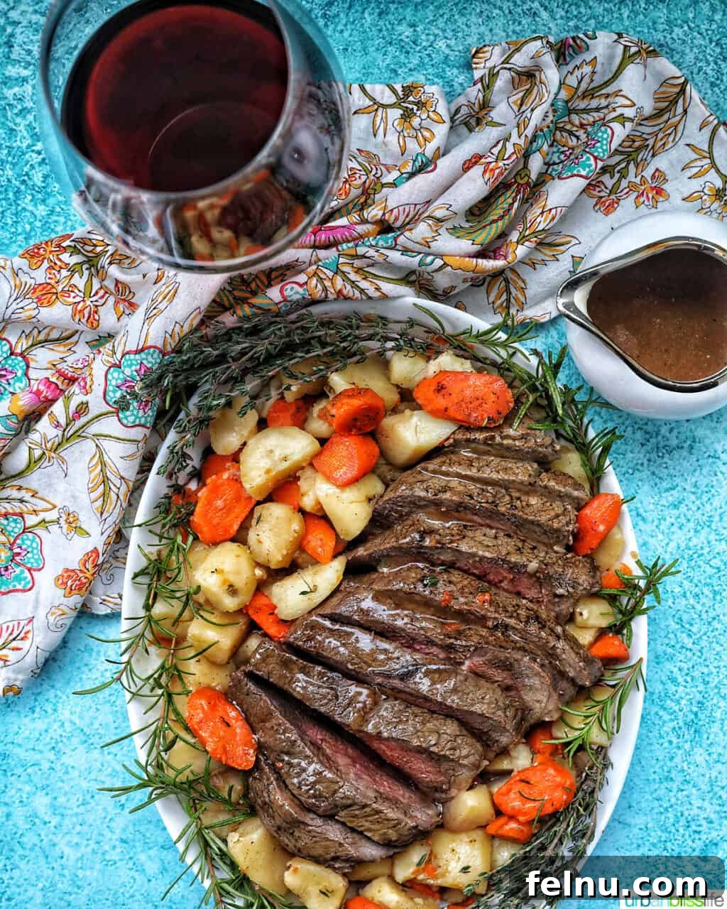 Tender Instant Pot Sirloin Tip Roast 21 Sliced sirloin tip roast surrounded by carrots, potatoes, and herbs with a side of gravy and glass of red wine.
