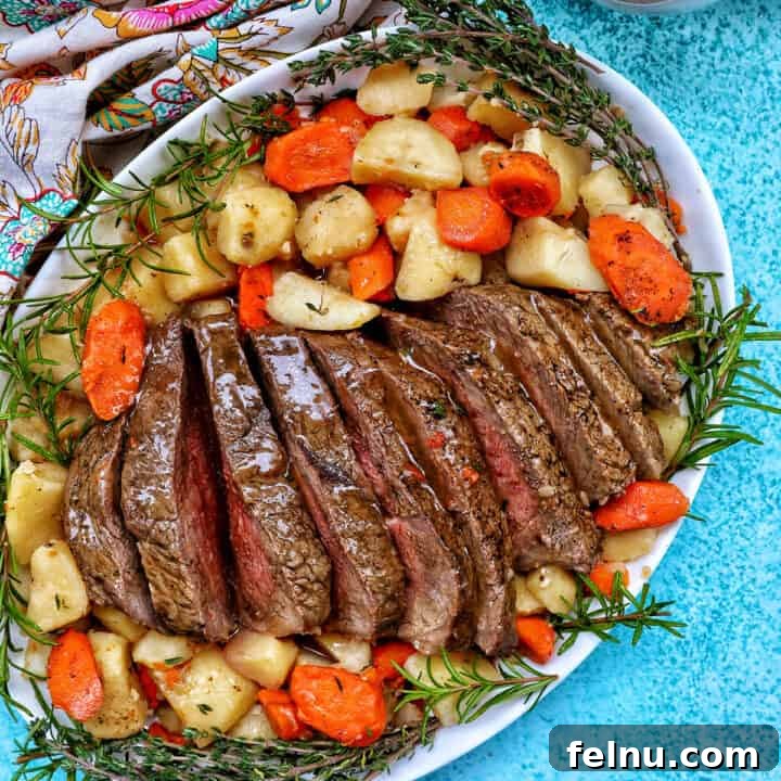 Tender Instant Pot Sirloin Tip Roast 23 Sliced sirloin tip roast surrounded by carrots, potatoes, and herbs with a side of gravy.