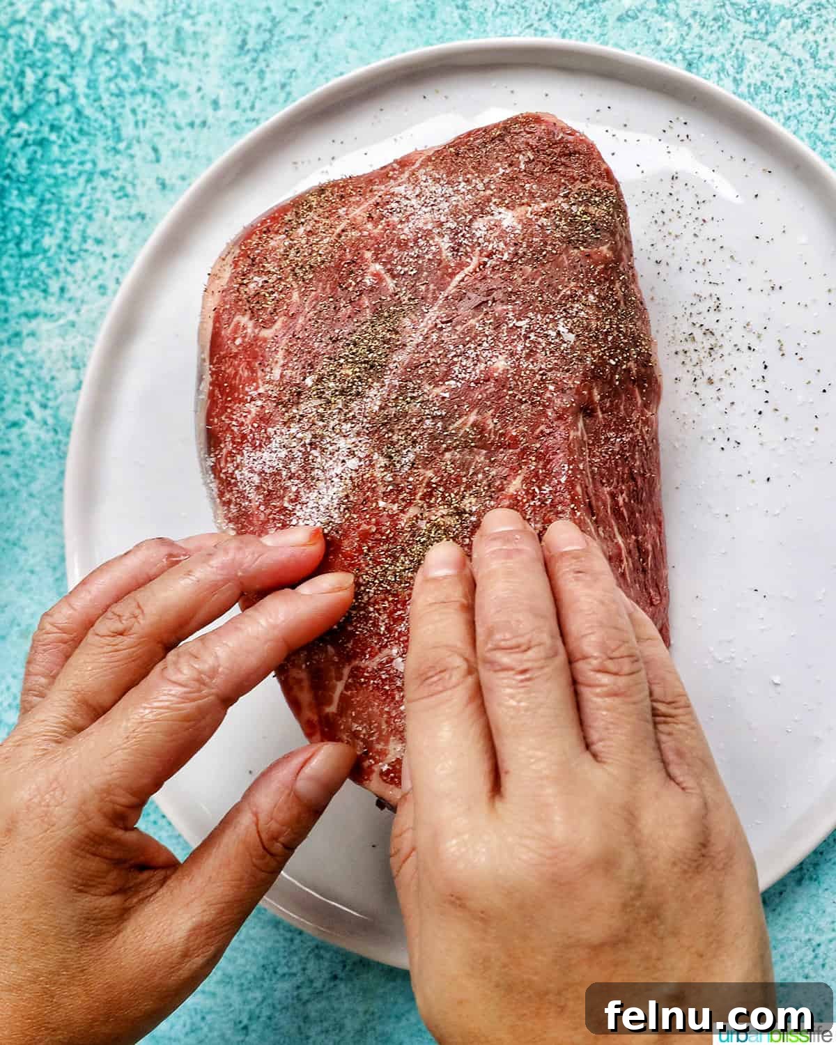 Tender Instant Pot Sirloin Tip Roast 5 two hands seasoning sirloin tip roast with salt and pepper on a white plate.