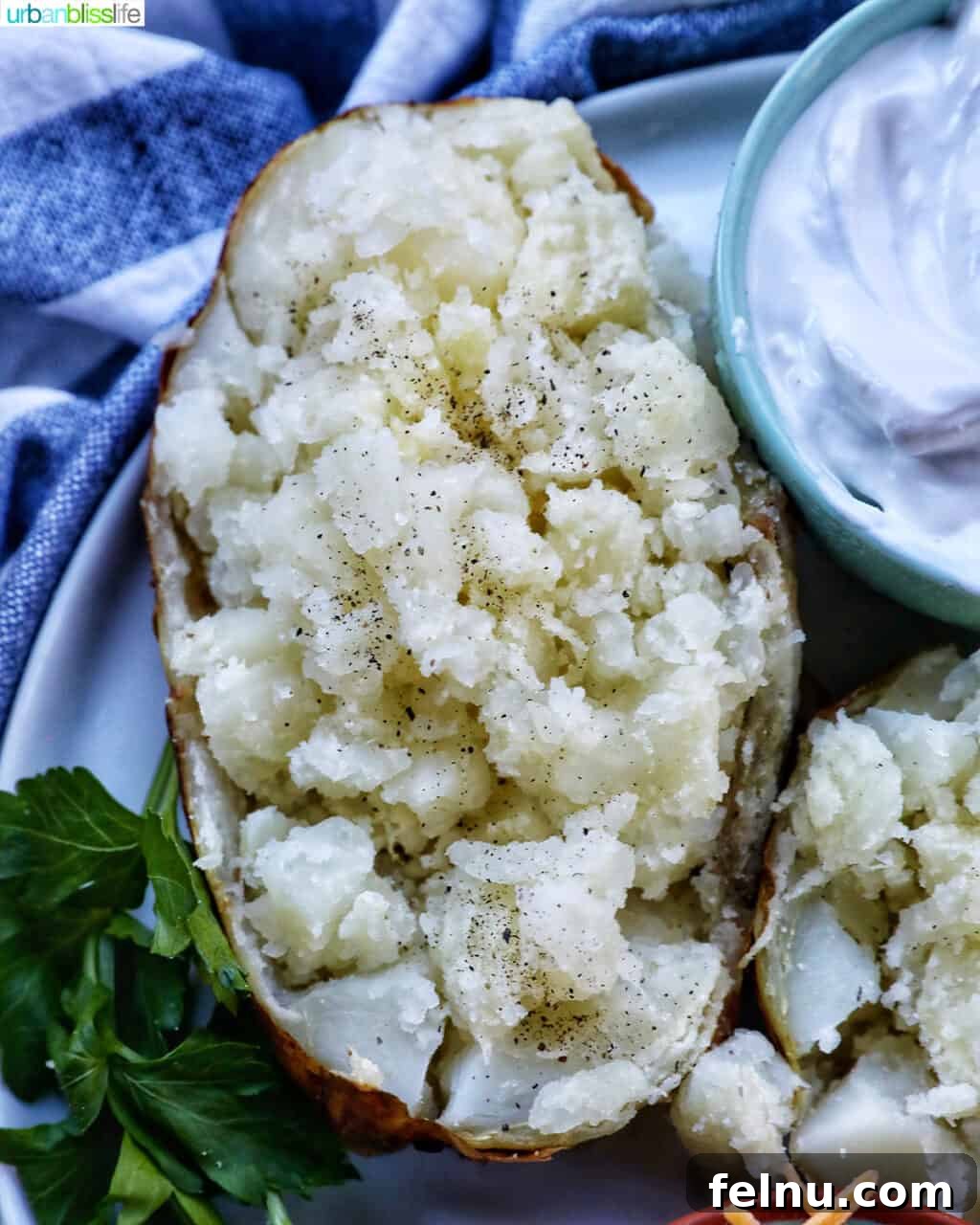 Crispy Fluffy Ninja Foodi Air Fryer Baked Potatoes 3 baked potato on a plate with side of sour cream and parsley.