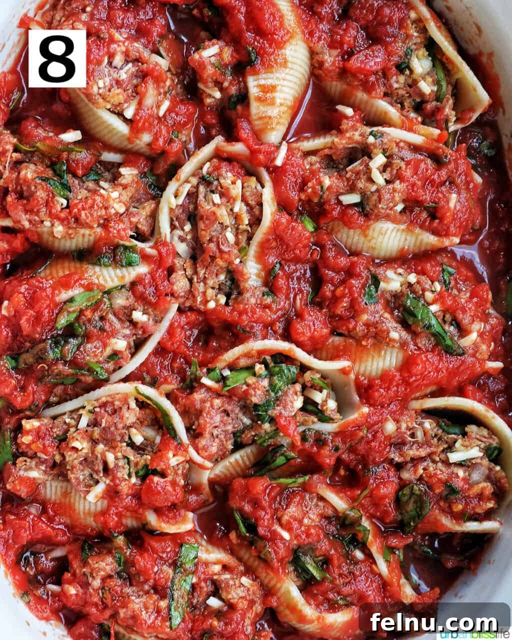 Hearty Dairy-Free Beef Stuffed Shells 12 An overhead view of stuffed shells with ground beef, now generously topped with more marinara sauce, preparing for baking.