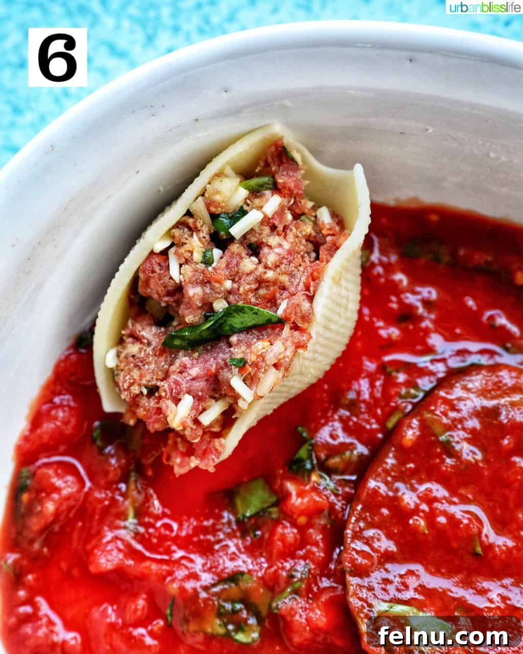 Hearty Dairy-Free Beef Stuffed Shells 10 A single uncooked stuffed shell with ground beef, perfectly placed on top of the marinara sauce in the casserole dish.