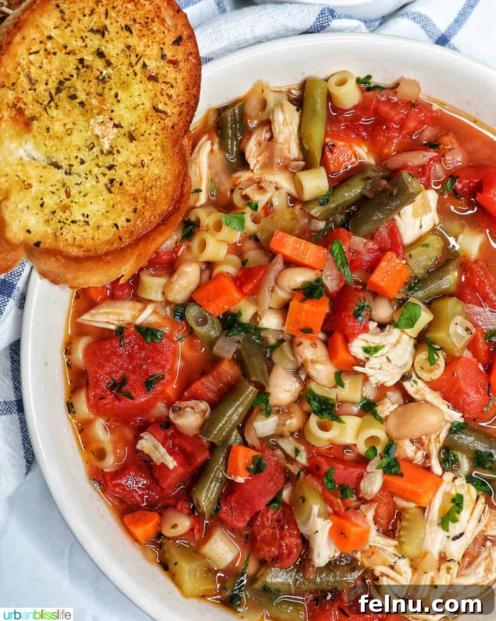Chicken Minestrone Soup Delight 2 Chicken Minestrone Soup served in a white bowl with a side of garlic bread, showcasing its vibrant colors and textures.