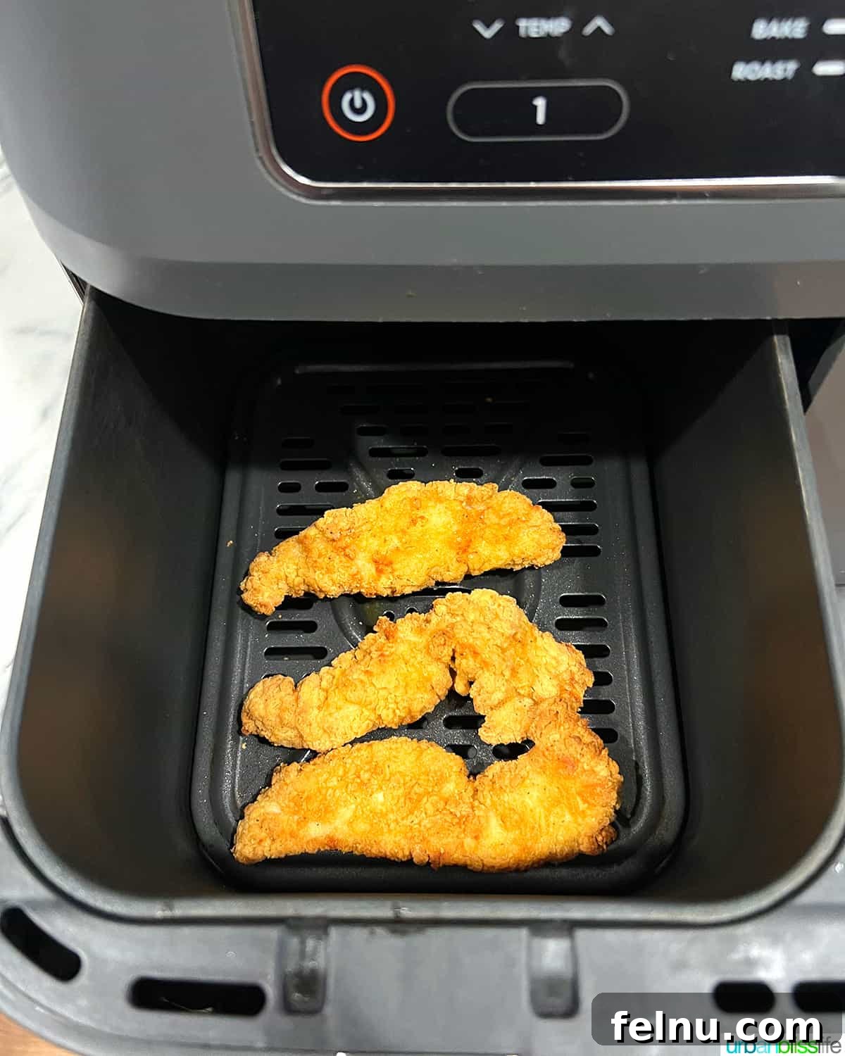 Air Fryer Frozen Chicken Tenders Made Perfect 7 Cooked frozen chicken tenders freshly removed from the air fryer basket, showing their golden-brown crispiness.