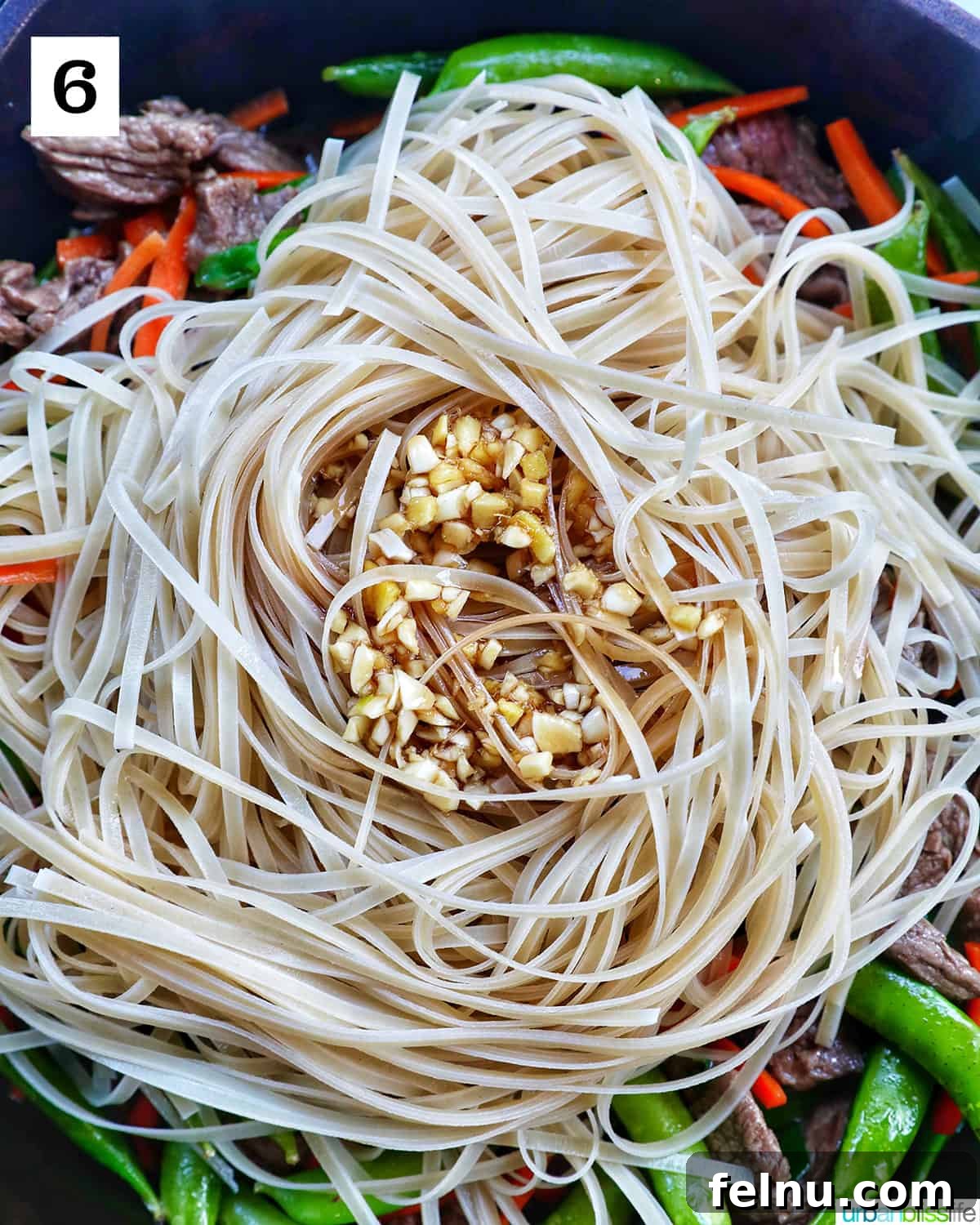Beef Pad Thai 11 Pad thai sauce on top of rice noodles on top of steak and vegetables in a pan.