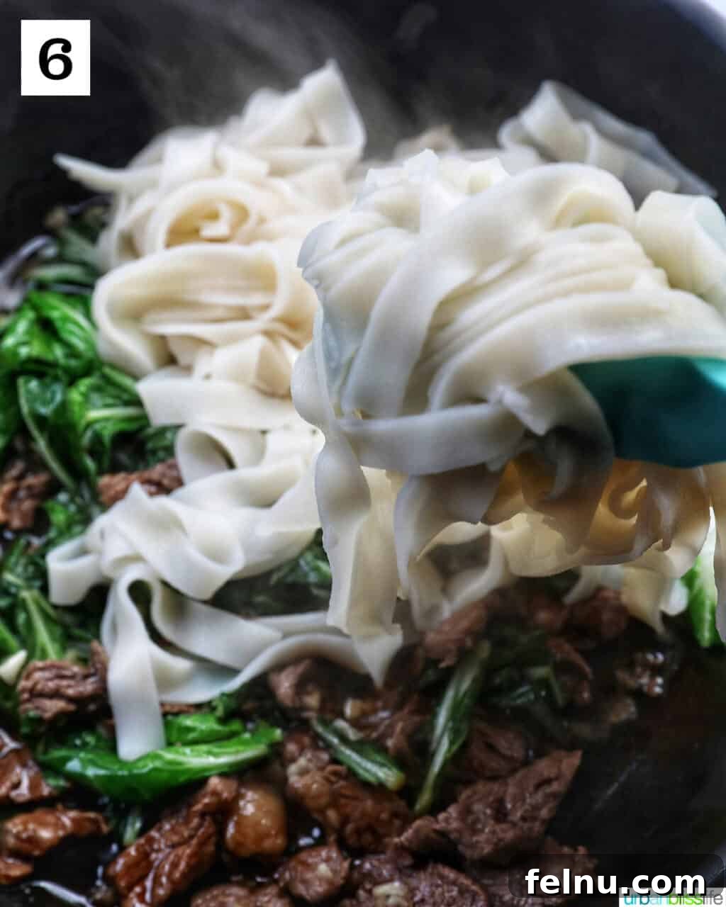 Savory Thai Beef Pad See Ew Noodles 11 Cooked wide rice noodles being added to the wok, combining with the beef, bok choy, and sauce for the Pad See Ew.