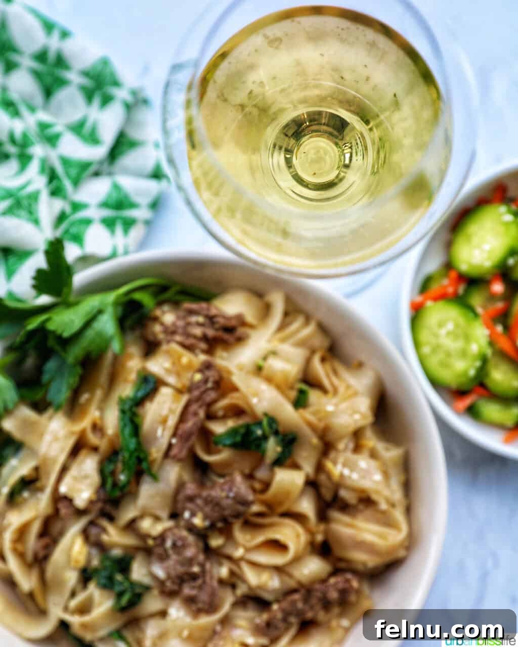 Savory Thai Beef Pad See Ew Noodles 15 A bowl of Beef Pad See Ew, perfectly plated, with a glass of crisp white wine and a small side of cucumber salad, suggesting a delightful meal pairing.