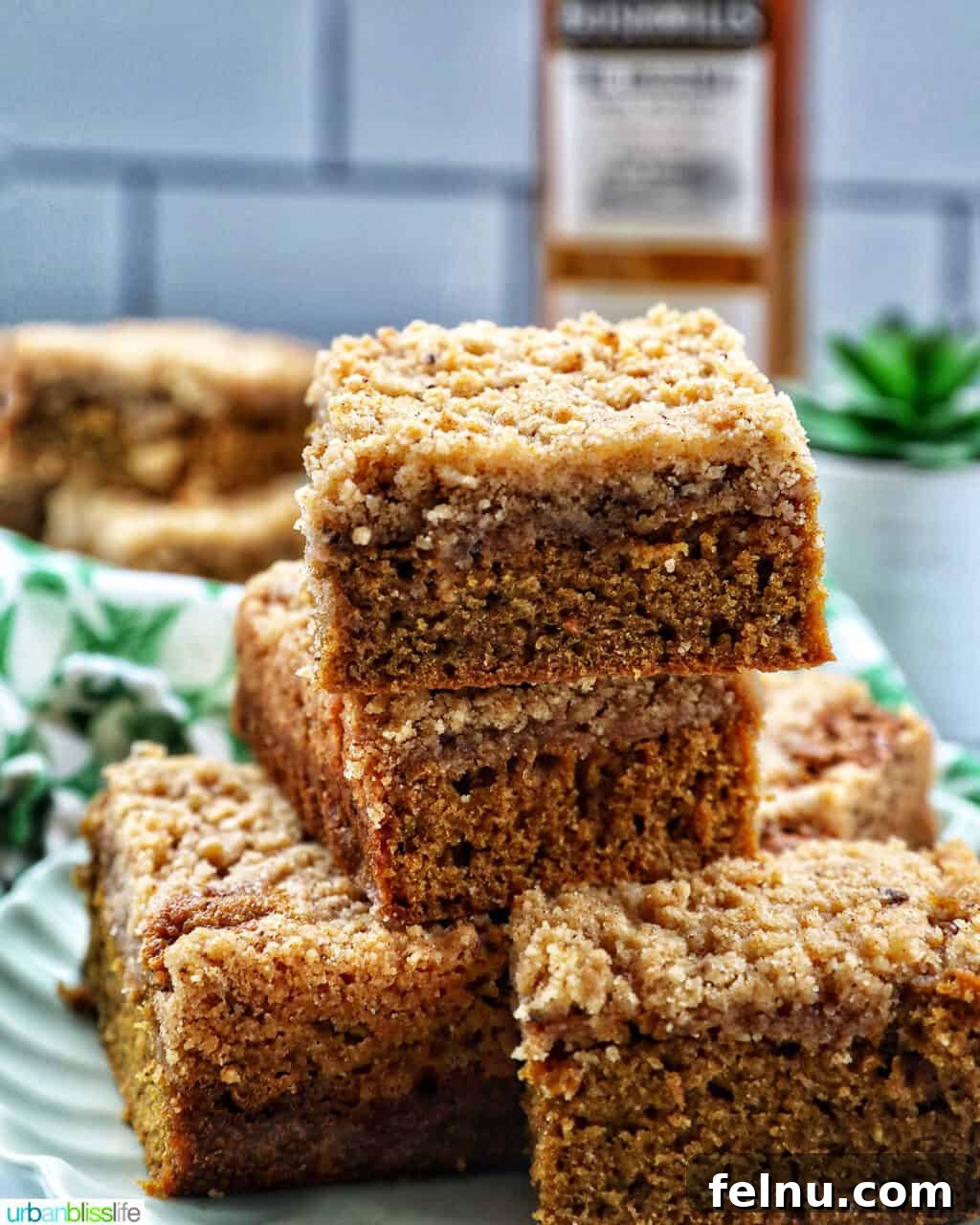 Emerald Isle Coffee Cake 2 A stack of golden Irish coffee cake slices on a vibrant green plate, accompanied by green patterned napkins and a bottle of Irish whiskey, inviting a delightful tasting experience.