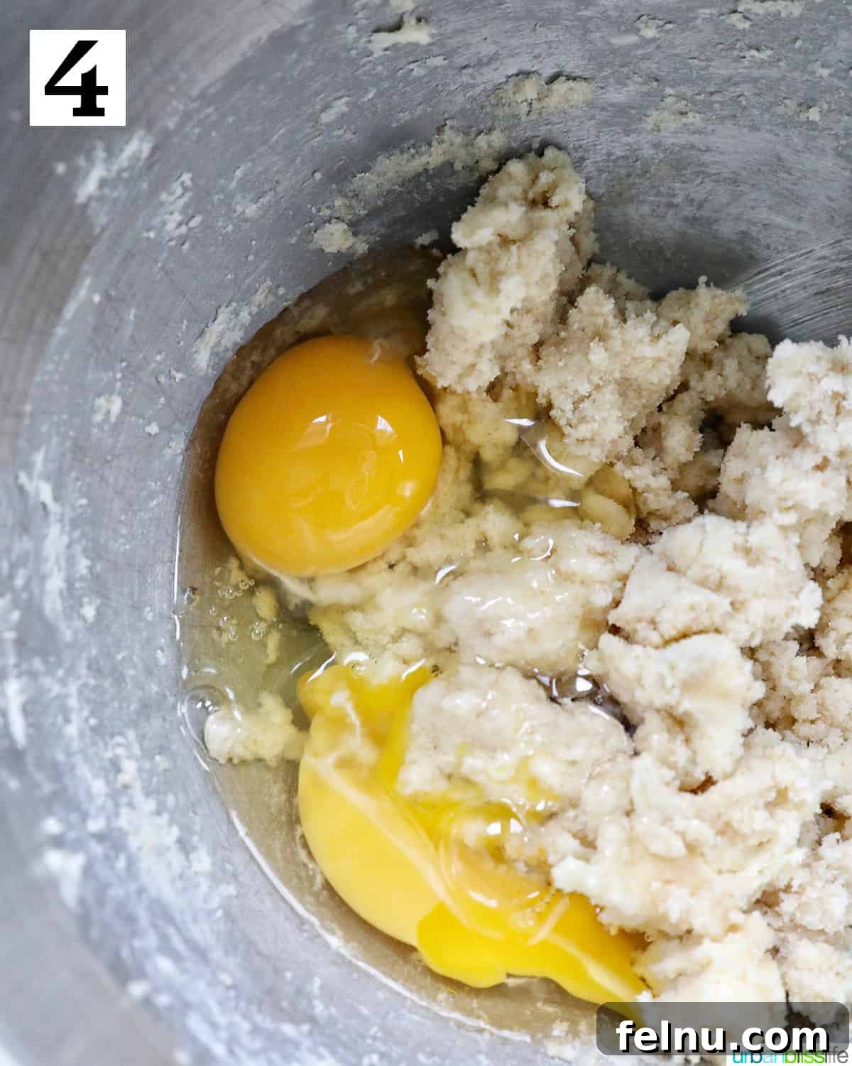 Emerald Isle Coffee Cake 11 Fresh eggs being carefully added to a stand mixer bowl containing creamed butter and sugar, forming a smooth, emulsified dough for the Irish coffee cake.