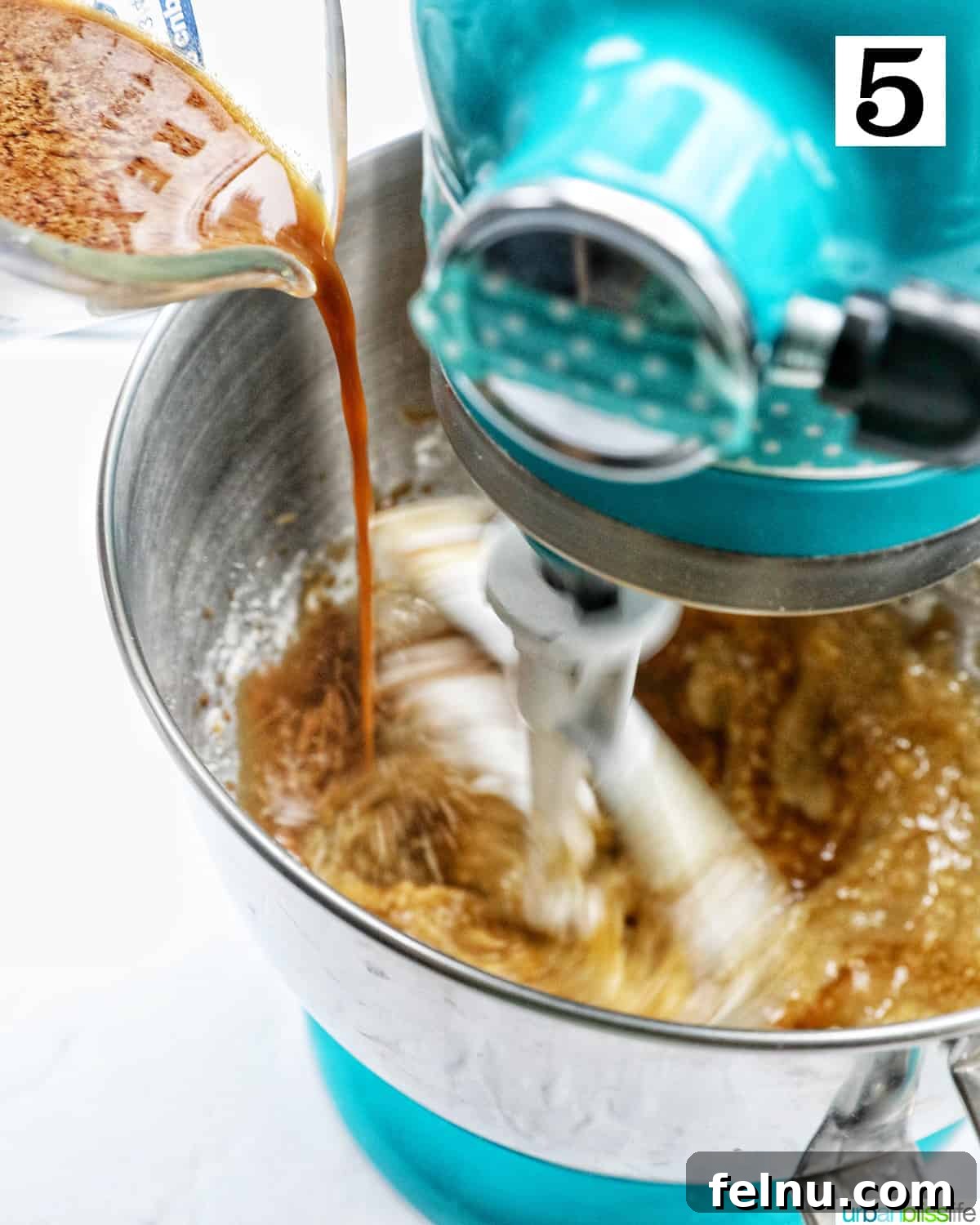 Emerald Isle Coffee Cake 13 The liquid mixture, including Irish whiskey and coffee, being poured into the stand mixer bowl to combine with the cake batter.
