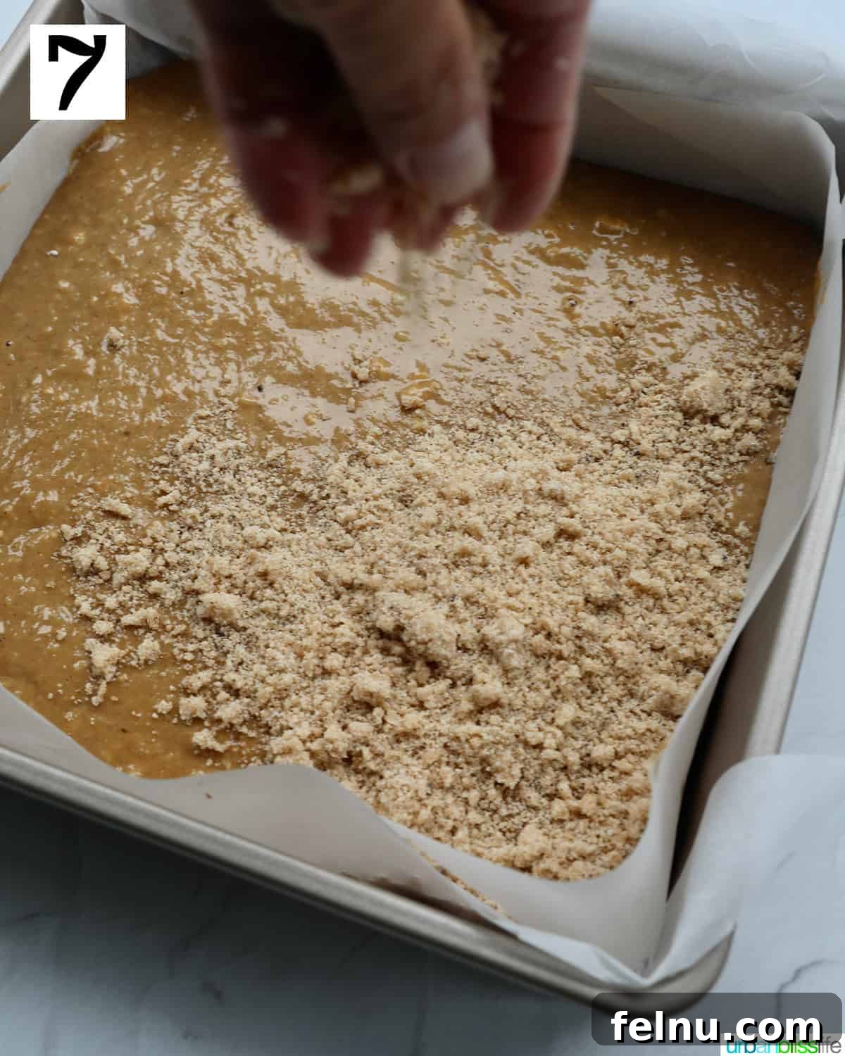 Emerald Isle Coffee Cake 16 A hand carefully spreading the crumbly streusel topping evenly over the wet batter in the baking pan, preparing the Irish coffee cake for baking.
