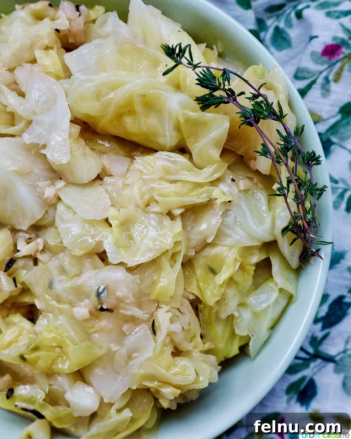 Effortless Instant Pot Cabbage 2 A close-up shot of a bowl of perfectly cooked Instant Pot Cabbage, garnished with fresh thyme sprigs and steam gently rising.