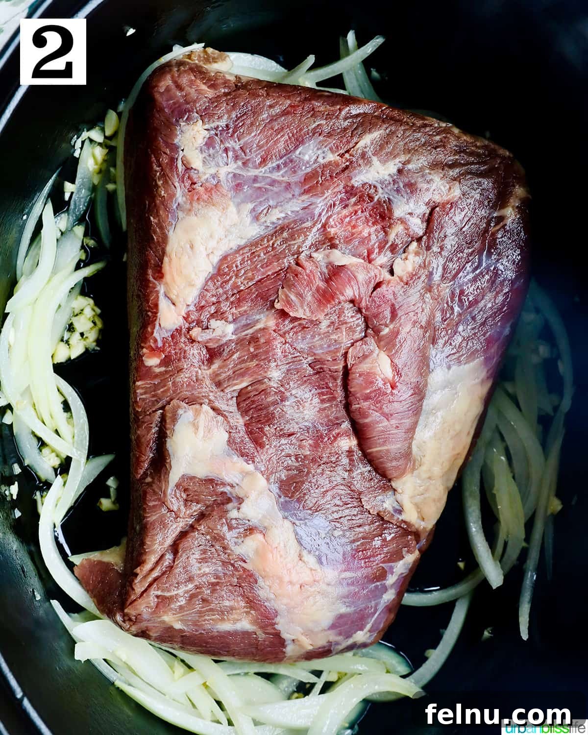 Tender Dutch Oven Brisket 6 raw beef brisket with garlic and onions in a dutch oven.