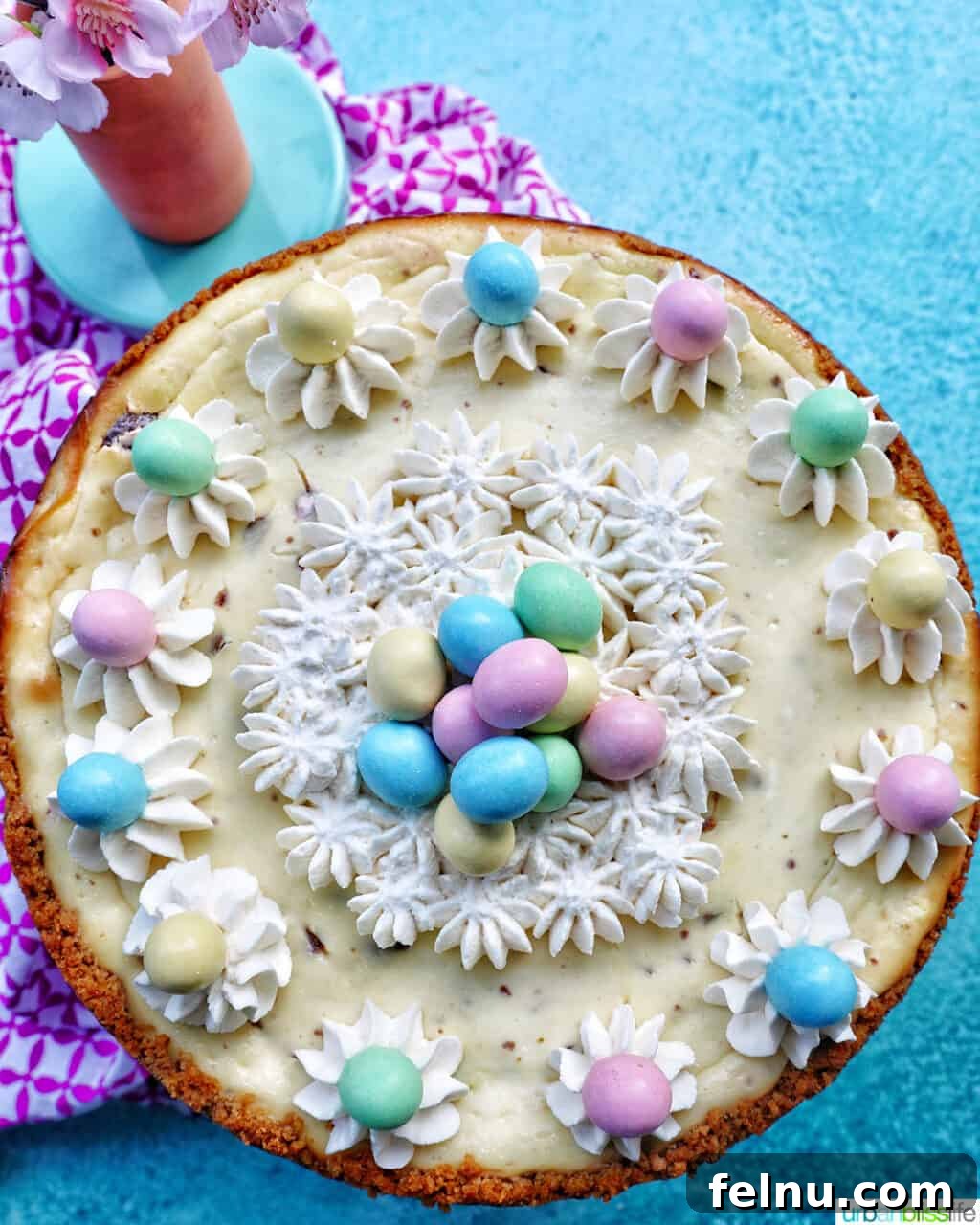 Easter Egg Delight Cheesecake 2 Overhead view of a beautifully decorated Easter egg cheesecake with mini chocolate eggs and whipped cream.