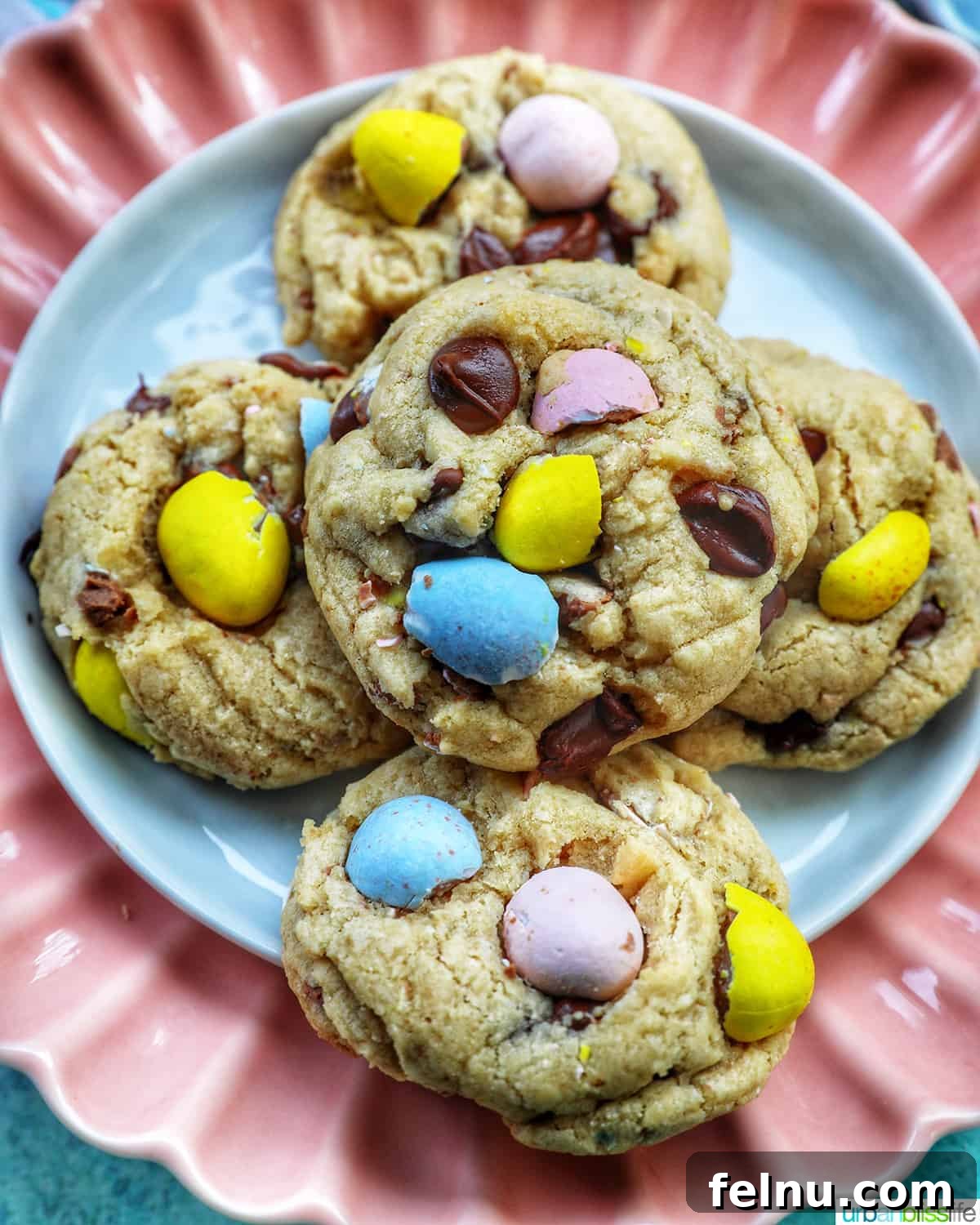 Effortless Mini Egg Cookies 2 A vibrant stack of Easter mini egg cookies arranged on a charming pink scalloped plate, inviting you to indulge in their festive sweetness.