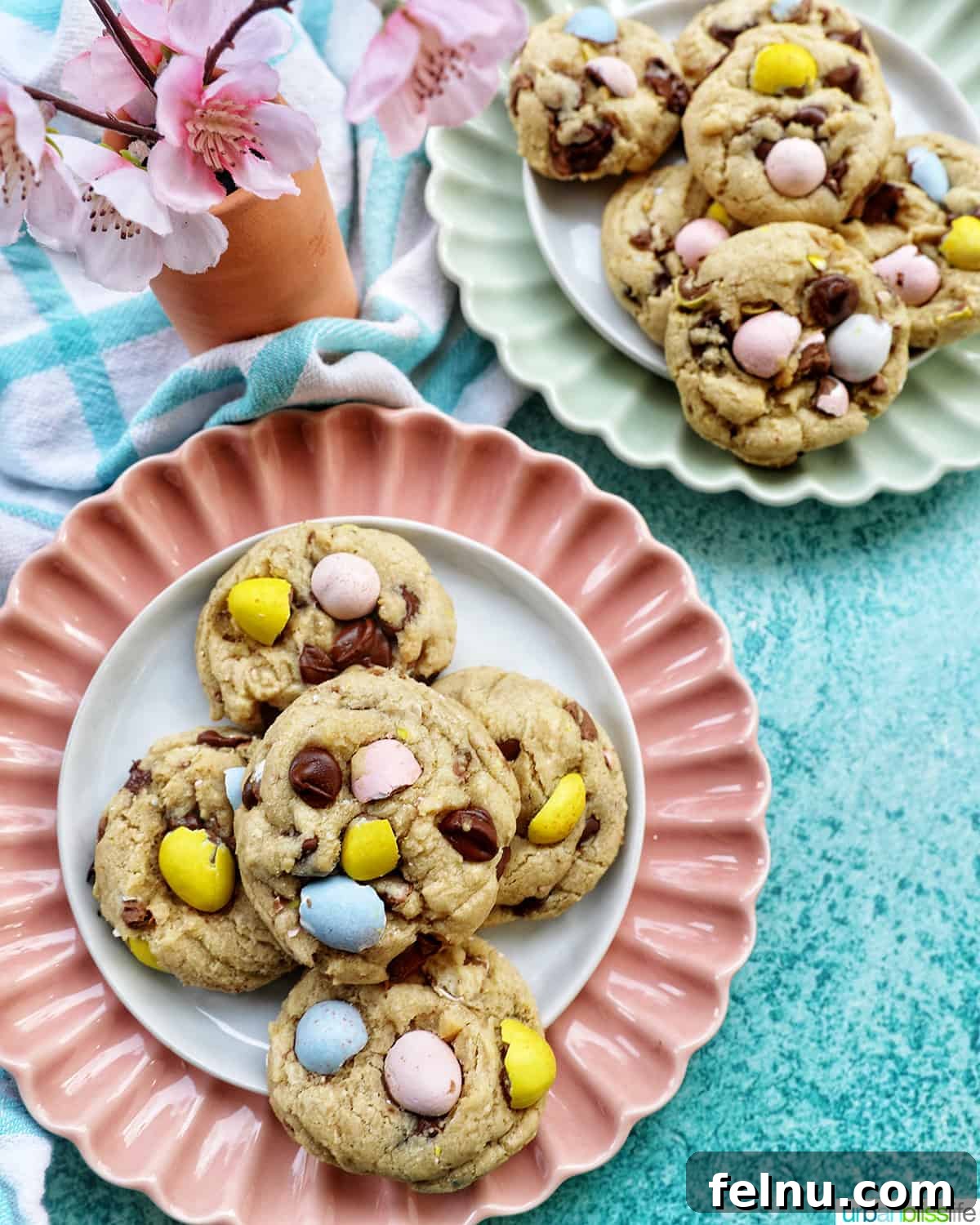 Effortless Mini Egg Cookies 14 A stack of delightful Easter mini egg cookies presented on a pink scalloped plate, alongside another stack on a green plate, ready to be enjoyed.