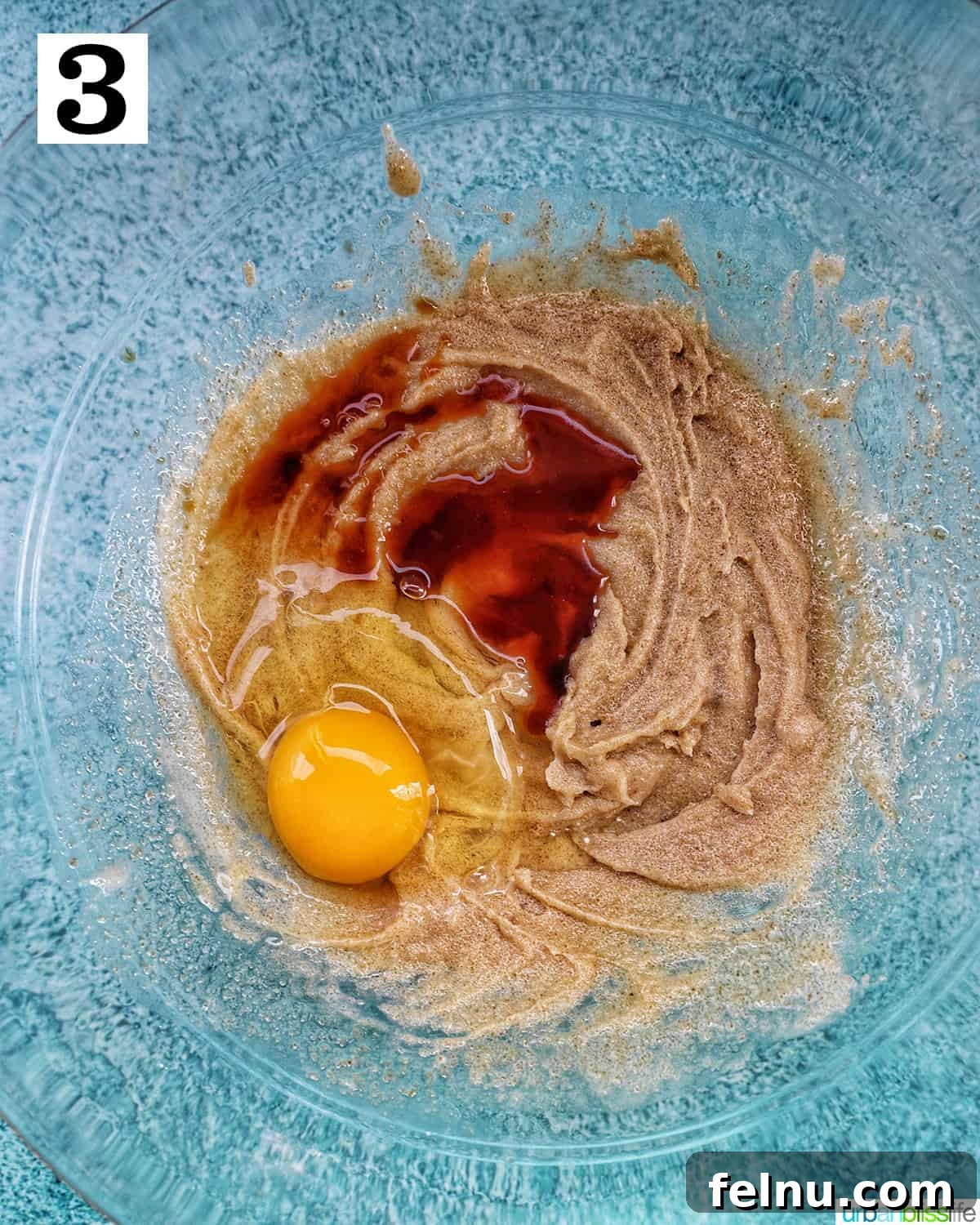 Effortless Mini Egg Cookies 8 A mixing bowl with wet ingredients, showing the egg and vanilla extract being beaten into the butter and sugar mixture.