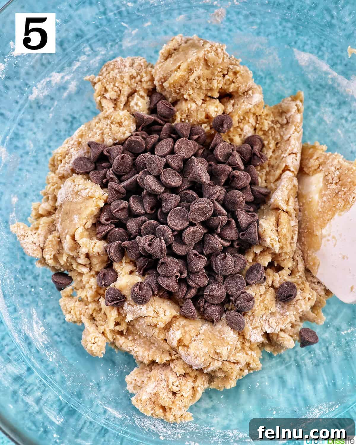 Effortless Mini Egg Cookies 10 Chocolate chips being folded into the cookie dough mixture with a spatula.