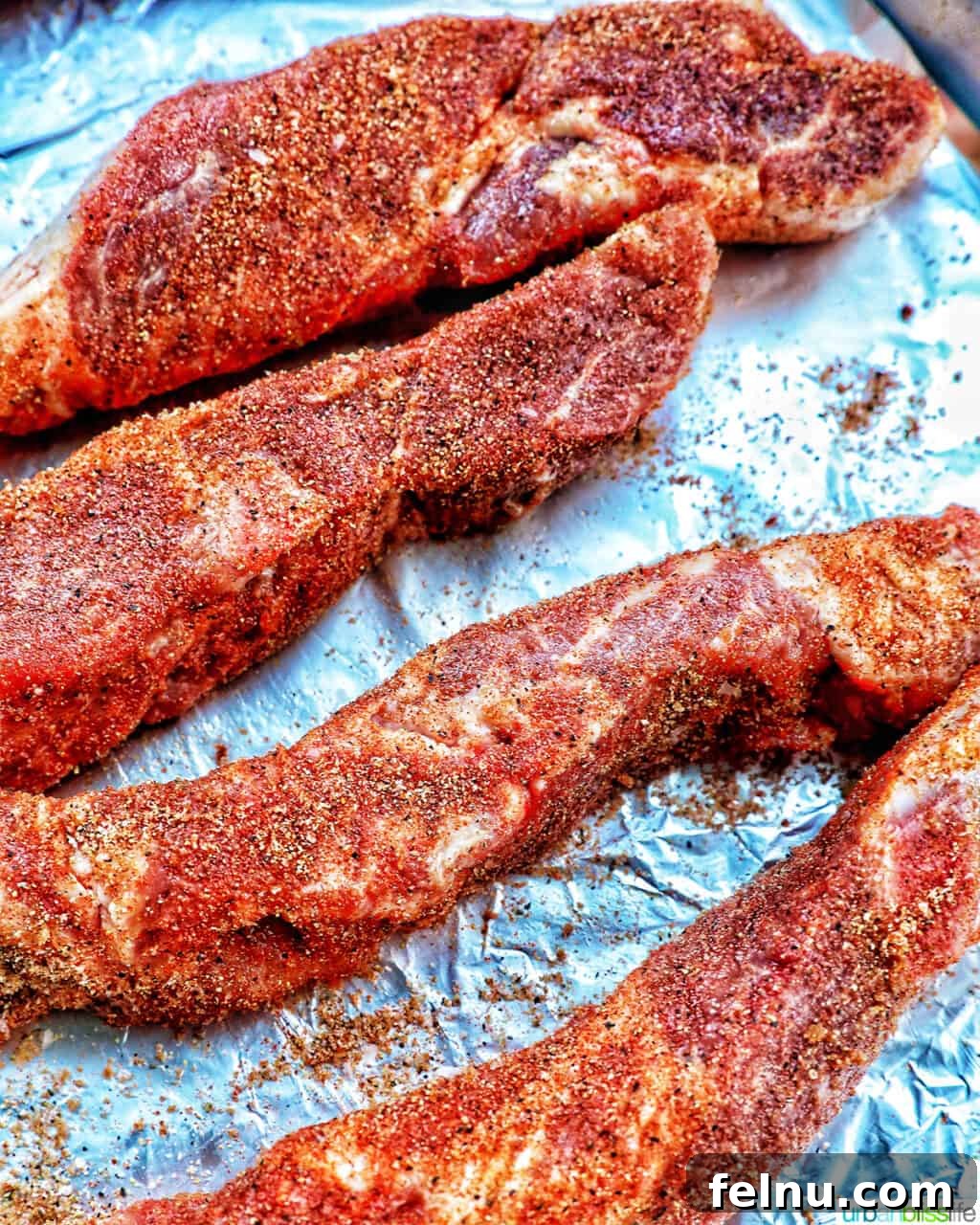Country style ribs seasoned on aluminum foil.