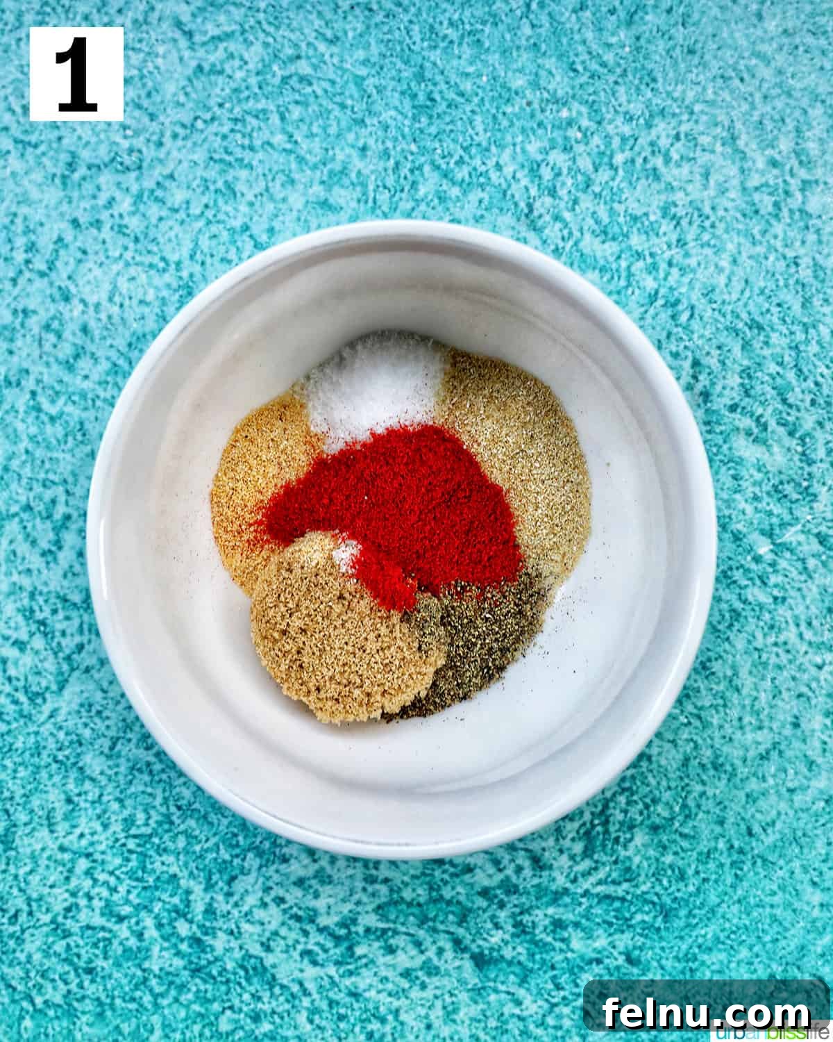 Herbs and seasonings in a white bowl on a blue background.