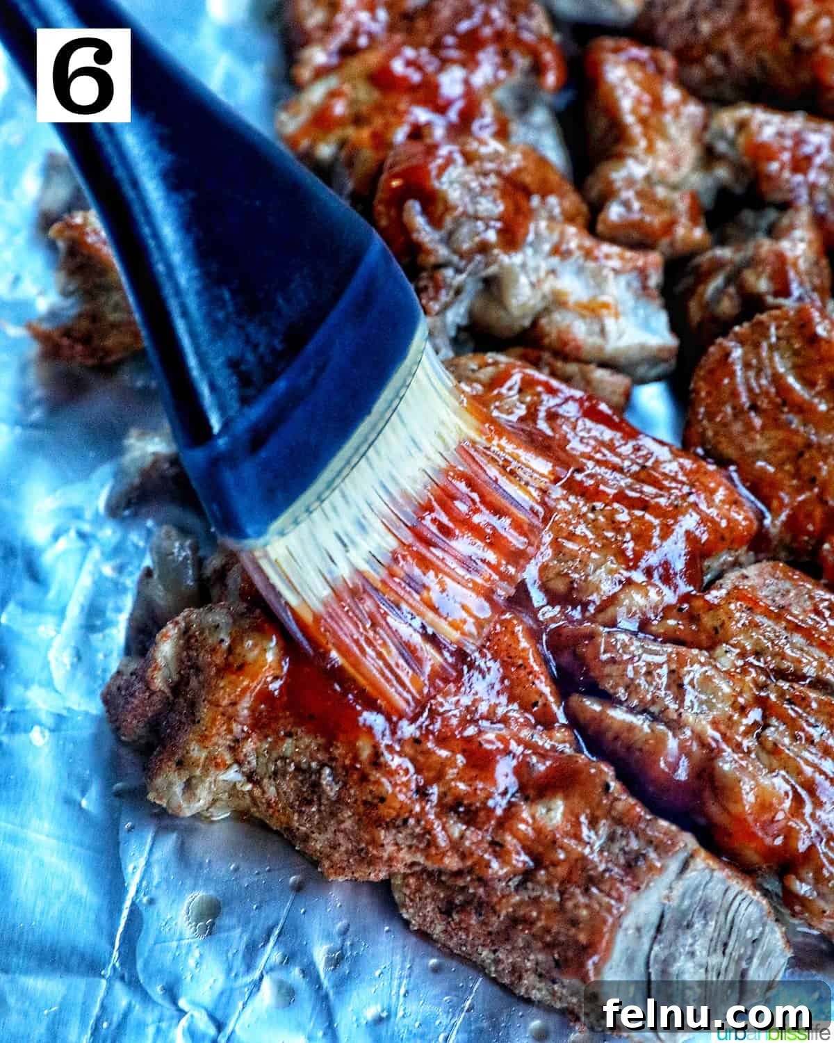 Pastry brush basting ribs with BBQ sauce.