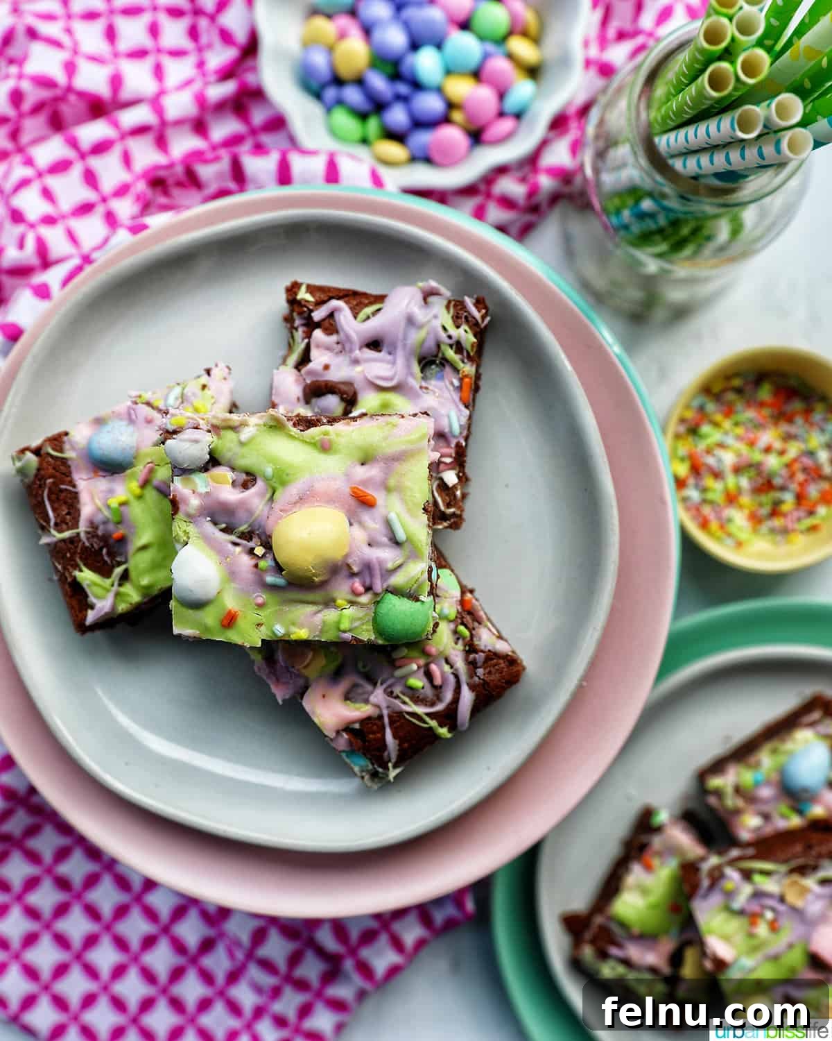 Easter Chocolate Squares 21 Stacks of colorful Easter brownies on white and pink plates, with sides of pastel M&Ms and sprinkles.