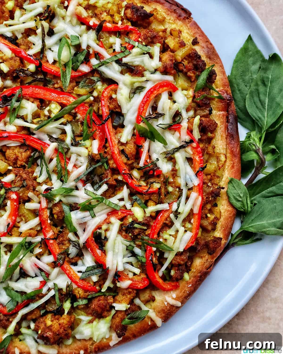 Thai Curry Pizza Delight 2 Thai curry pizza on a white plate with side of Thai basil