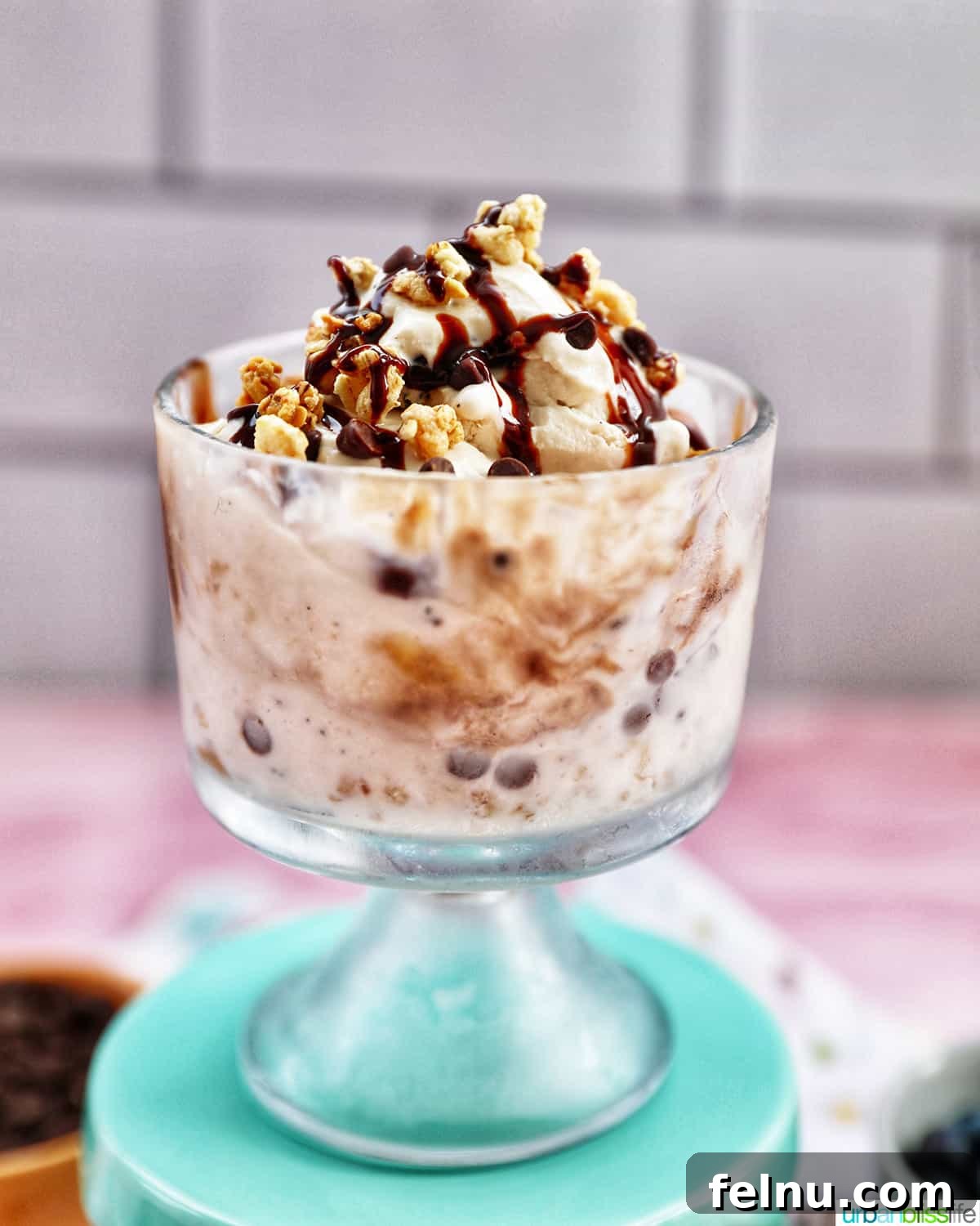 Ice Cream Parfait: A Symphony of Flavors and Textures 3 Parfait bowl with an ice cream parfait, generously topped with granola, chocolate syrup, and mini chocolate chips on a vibrant kitchen towel.