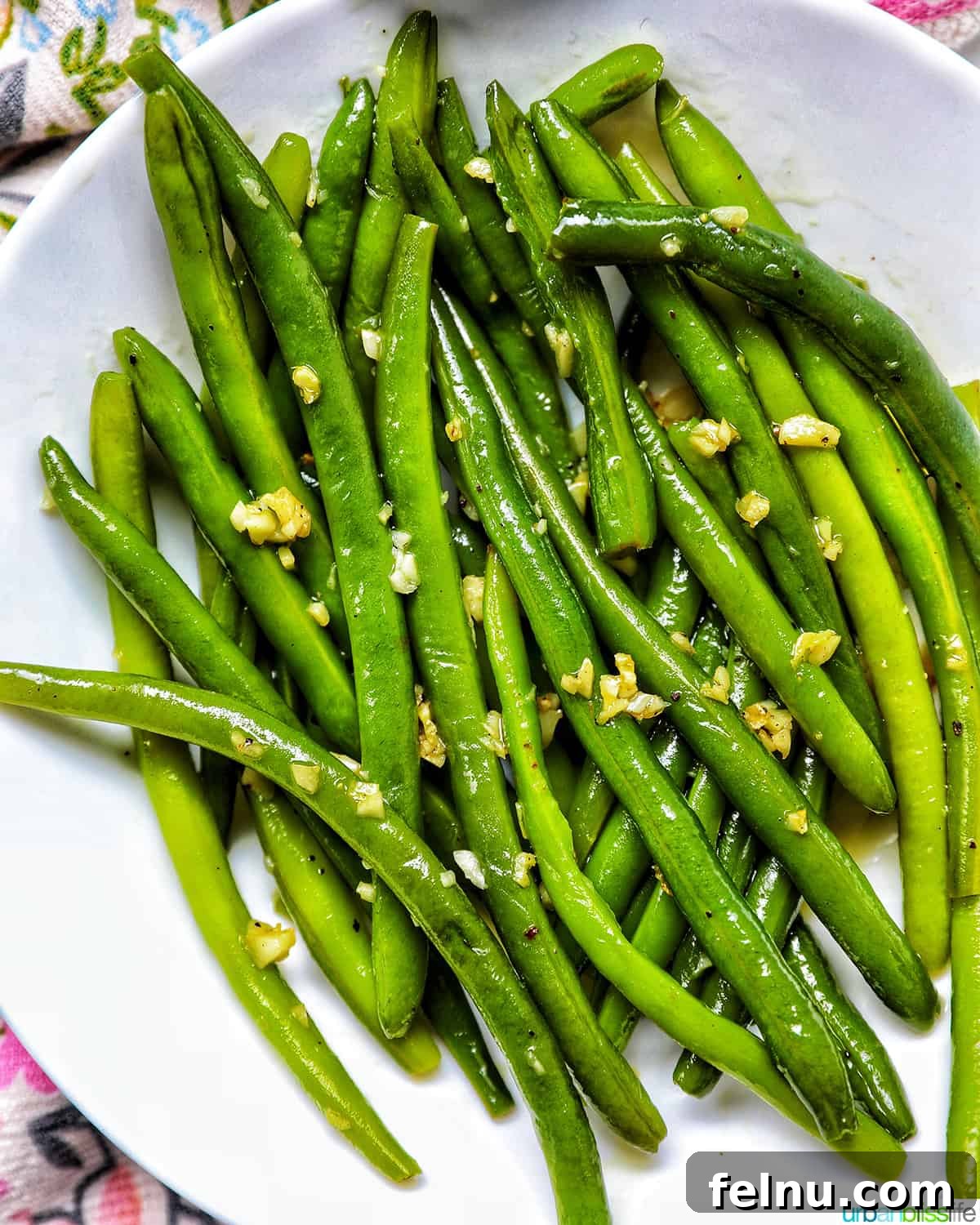 Green beans with garlic in a white bowl, showcasing their vibrant color and appealing texture.