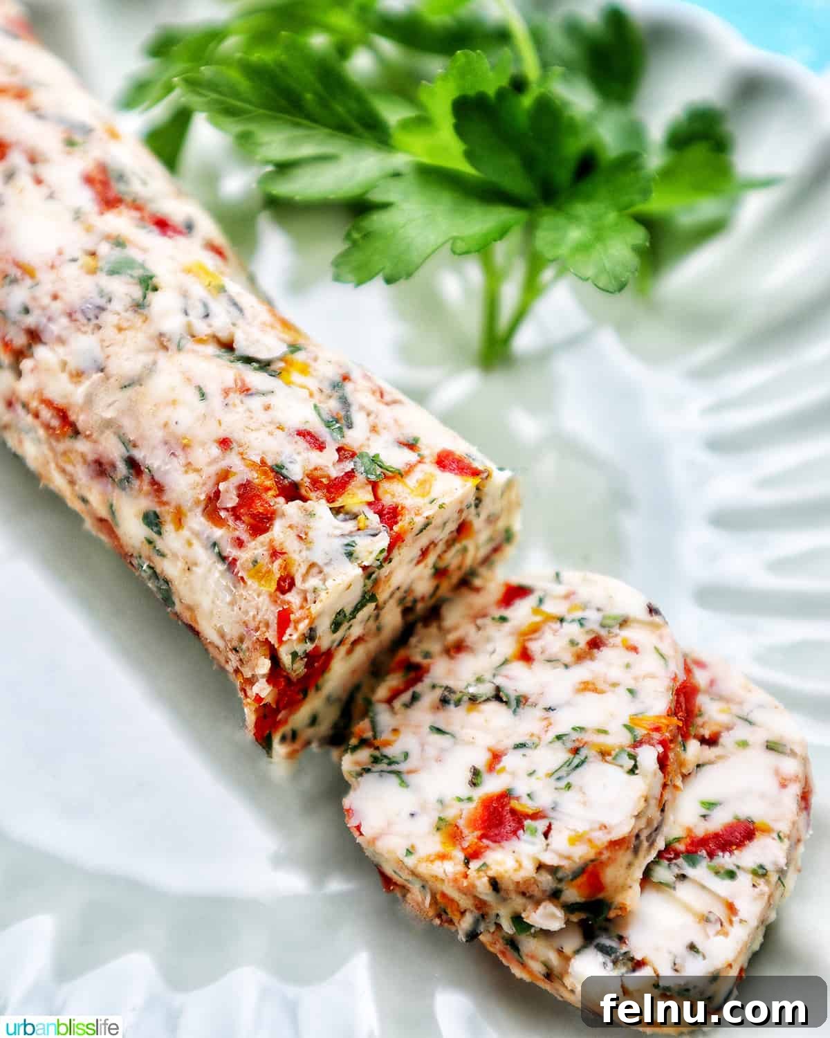 Slices of sun-dried tomato butter on a green plate with herbs.