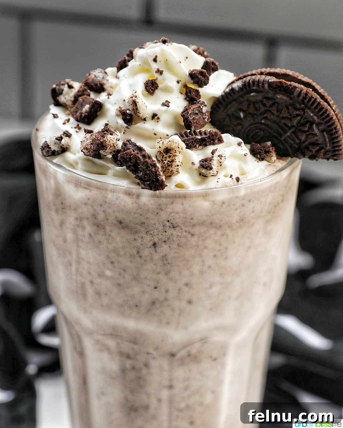 Creamy Dream: The 3-Ingredient Cookies and Cream Milkshake 3 Closeup of a tall glass filled with a thick, creamy Cookies & Cream Milkshake, adorned with a swirl of whipped cream and a sprinkle of crushed Oreo cookies.
