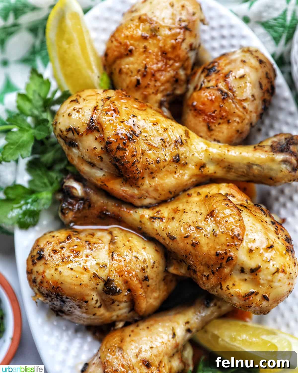 Instant Pot Chicken Legs 3 Plated Instant Pot Chicken Drumsticks with parsley and lemon wedges.